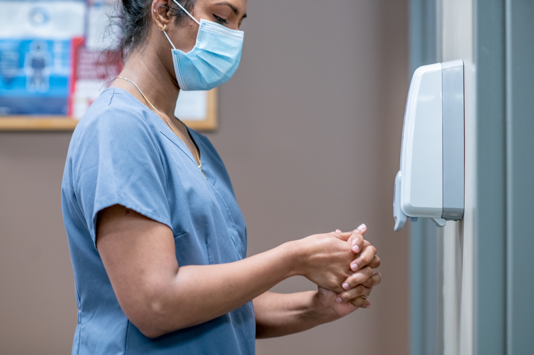 healthcare worker using hand sanitizing dispenser