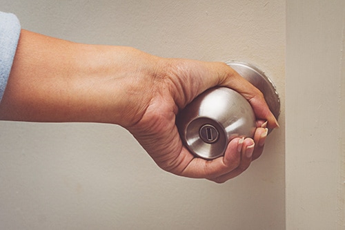 Woman using a door knob to open a door