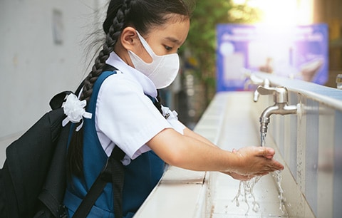 Student washing her hands at an outdoor wash basin.