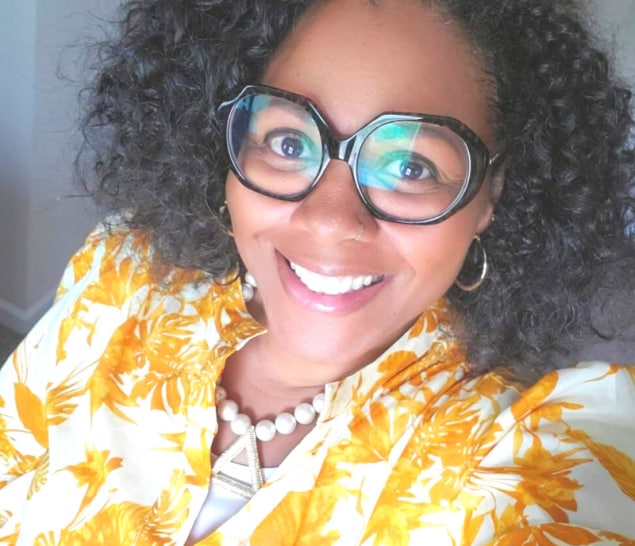 Melinda Jordan in a yellow and white jacket with stylish eyeglasses from her collection