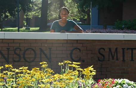 Kameron Sheats standing beside the wall at the entrance to Johnson C. Smith University