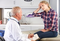photo: girl with head pain talking to a doctor