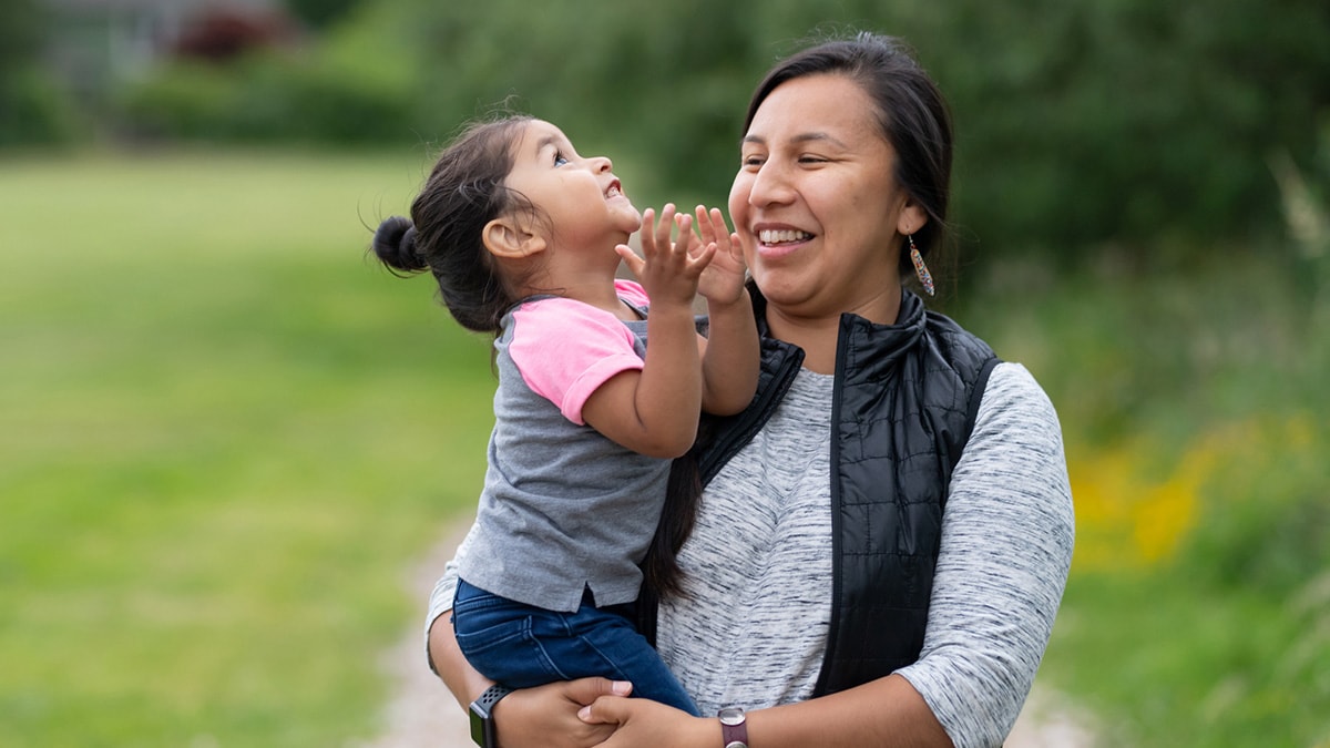 A Native American mother smiles while holding her child.