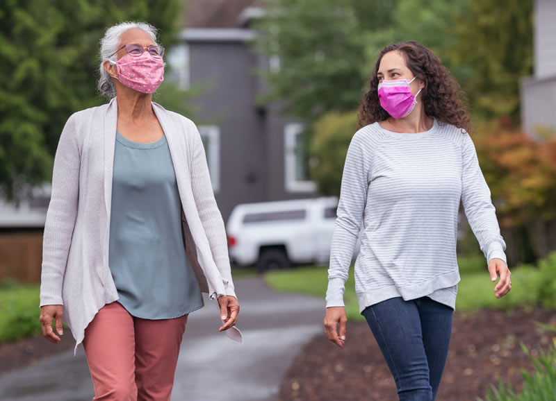 Dos mujeres que llevan mascarilla caminando afuera