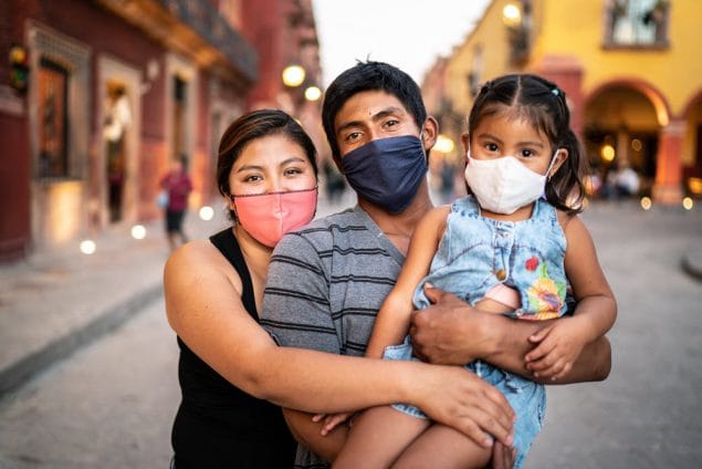 Latino family outdoors wearing masks