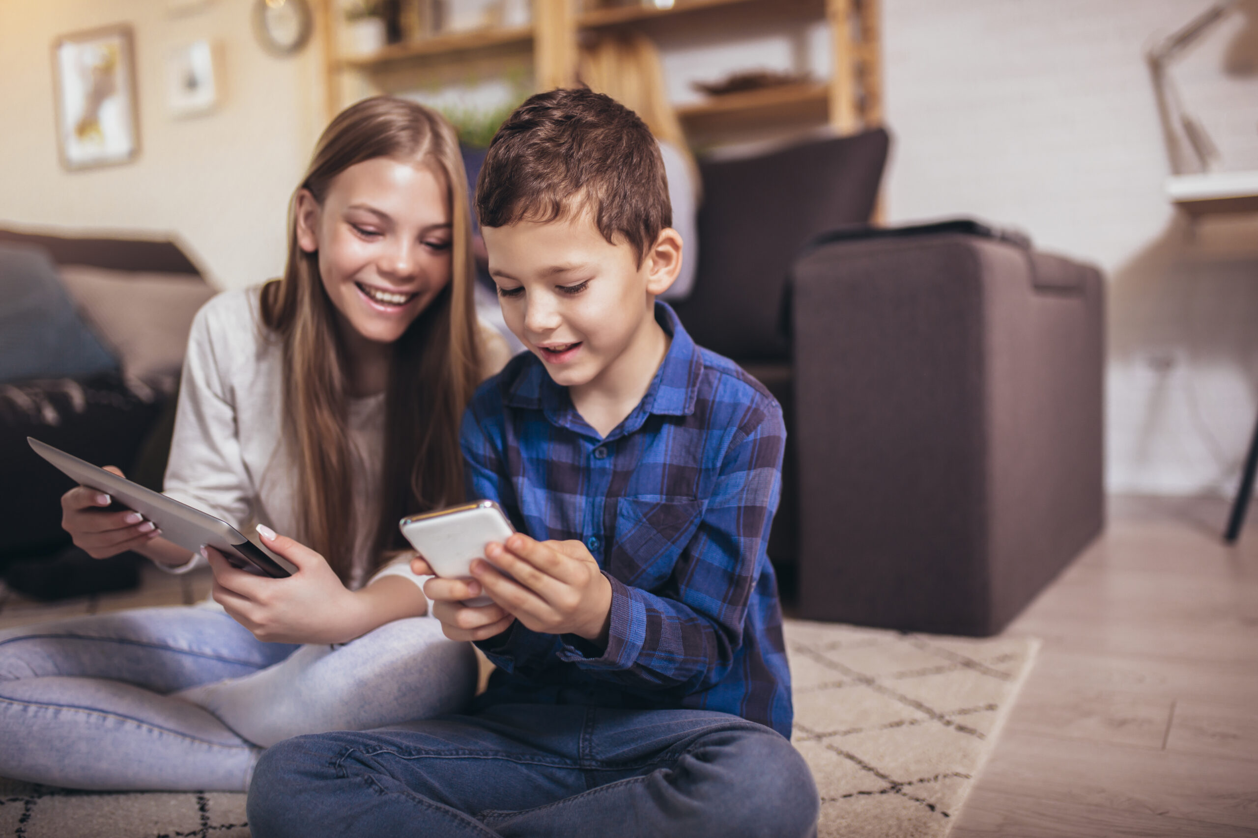 2 kids using a smart phone and tablet.