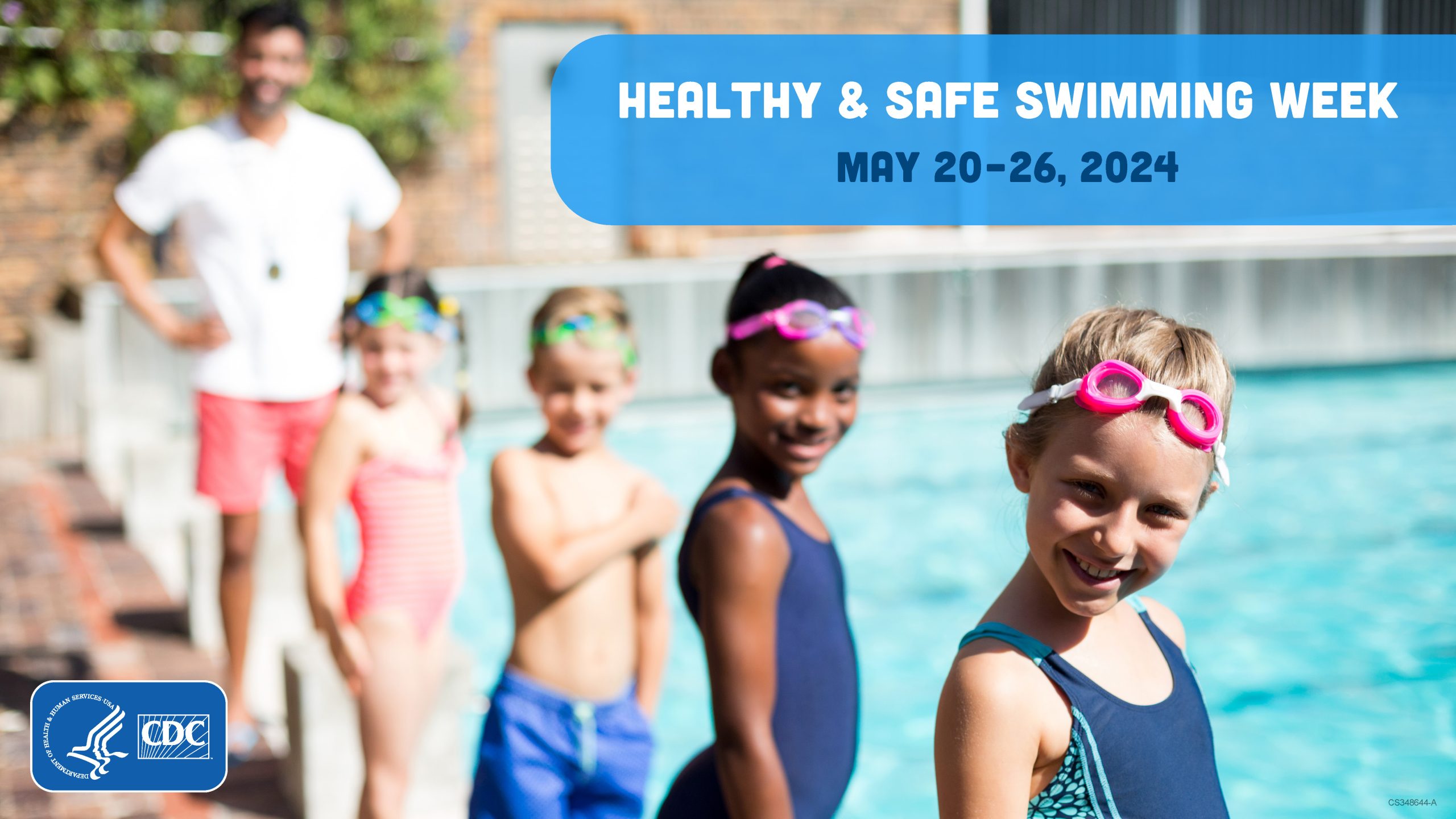 A group of children around 8-10 years old with goggles on their heads standing and the end of the pool next to each other and smiling.