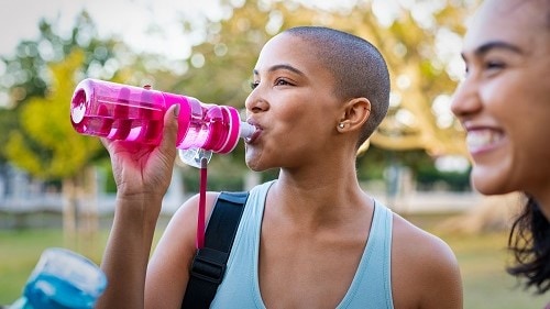 Woman drinking water from a refillable bottle.