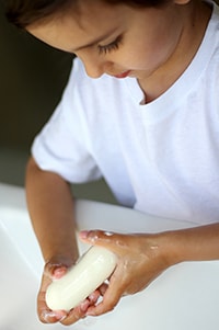 Child washing hands with soap and water.
