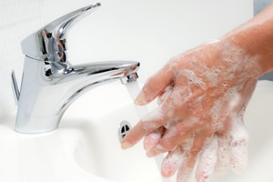 Osoba mytí rukou mýdlem a vodou