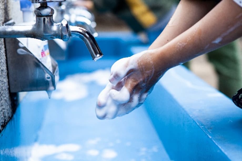 A child scrubbing his hands with soap and water in sink