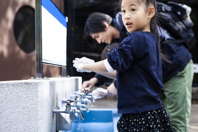 Girl washing hands in sink after touching animal