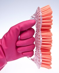 Pink gloved hands and cleaning brush.