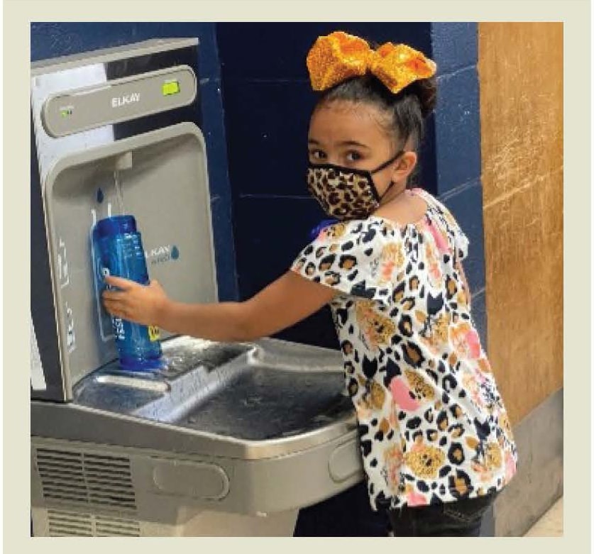 Girl refilling her water bottle at water bottle refilling station.
