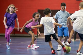 A group of students playing soccer in a gym