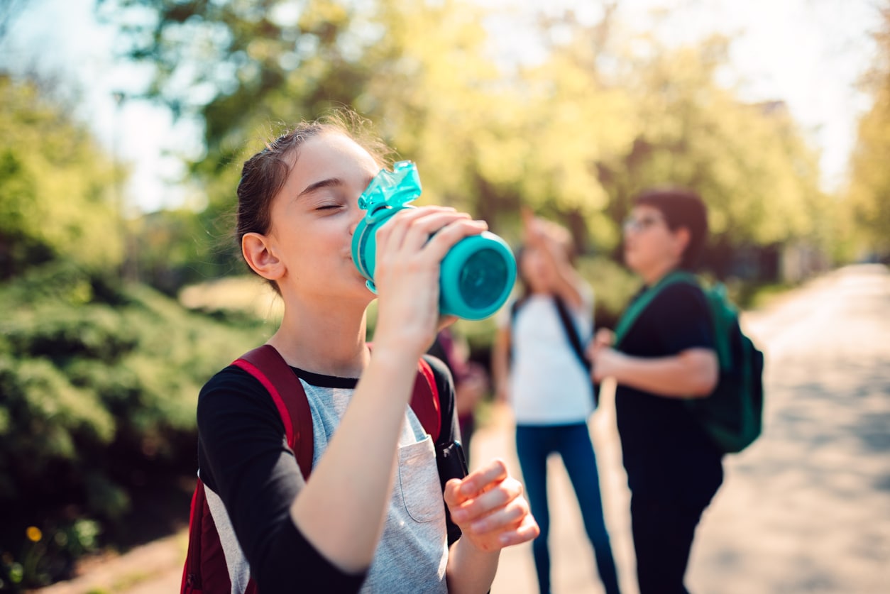 Young girl drinking from reusable water bottle