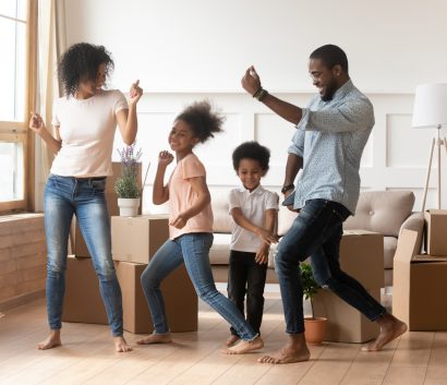 Family of four practicing new dances at home in living room. 