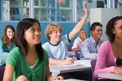Teenagers in class, one with hand raised