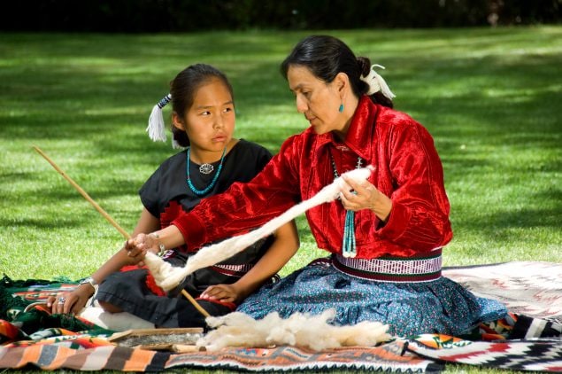 Native American mother demonstrating to daughter how to weave.