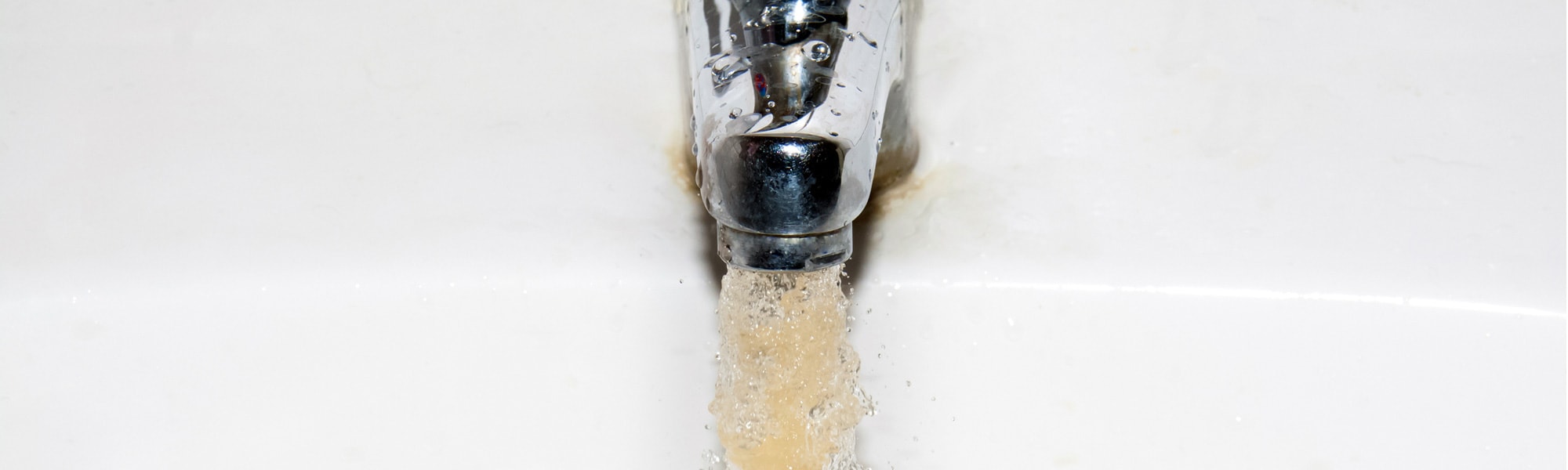 Image banner of dirty water coming out of a sink faucet