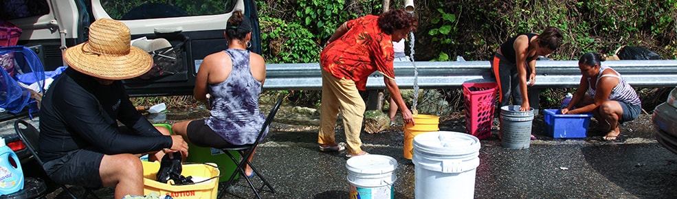 People washing clothes in buckets on the side of the road