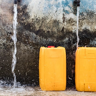 Water pouring into a yellow portable storage container