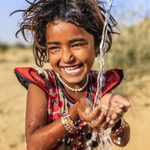 Girl playing in running water in India