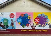 Painted mural about handwashing on the side of a building.