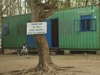 Tree-mounted sign outside ABHR production facility in Amuru, Uganda reading, “Together we will kick COVID-19 out of Uganda.”