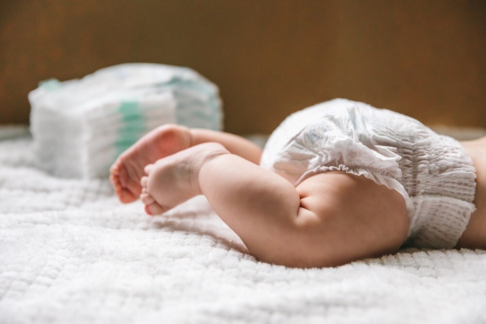 A baby in a diaper at the age of two months and a stack of diapers