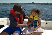 Photo of a father putting a life jacket on his daughter