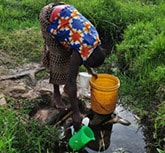 A woman collecting water from a river in Kenya