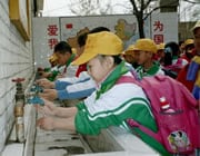 Chinese school children washing their hands at an outdoor washing station.