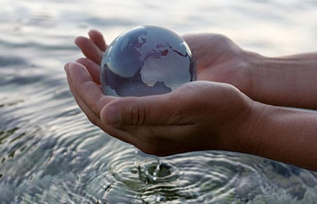 hands picking a globe up out of the water