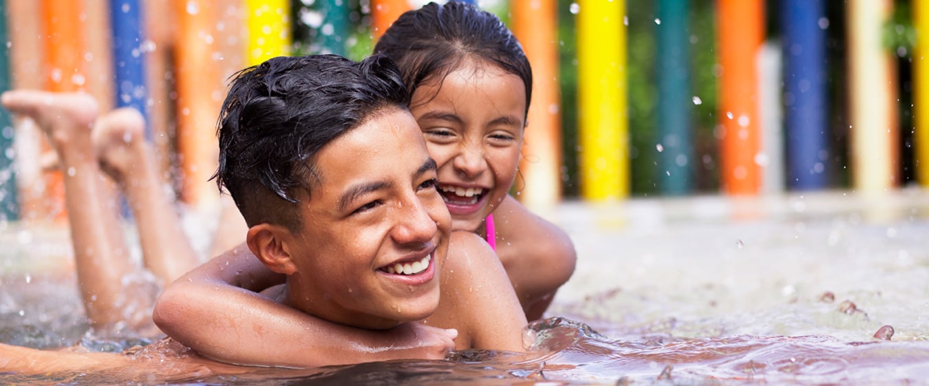 Two children smiling and playing in water.