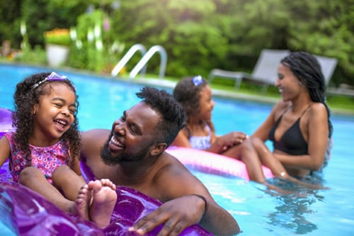 A family with two daughters swimming at backyard pool