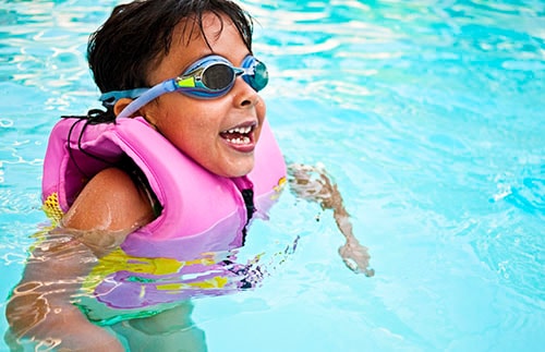 little girl with goggles swimming