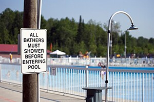shower next to pool with sign informing swimmers that they must shower before entering pool