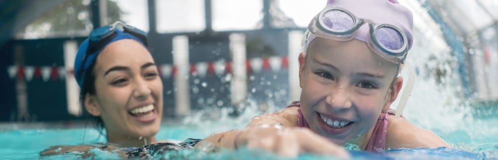 Imagen de una niña con una instructora de natación