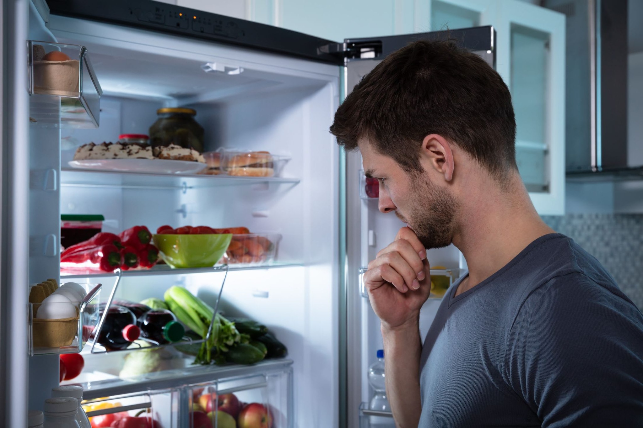 Un joven buscando algo de comer en un refrigerador