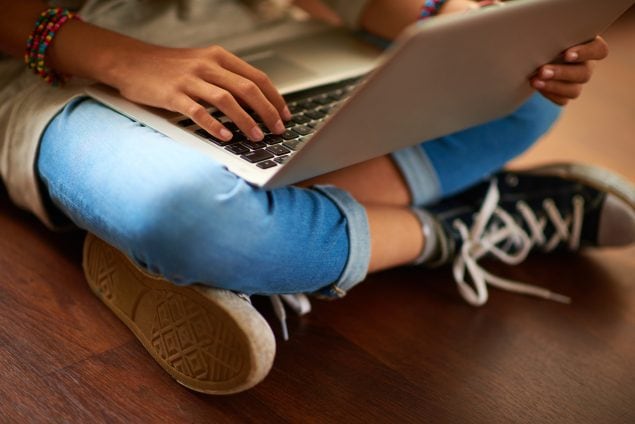 Close-up of laptop on crossed legs of girl