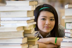 A female student sitting in front of a stack of books