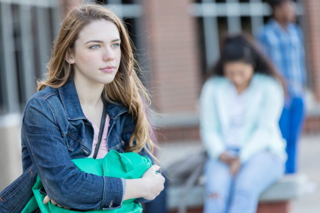 Teenage girl daydreams as she waits for school bus