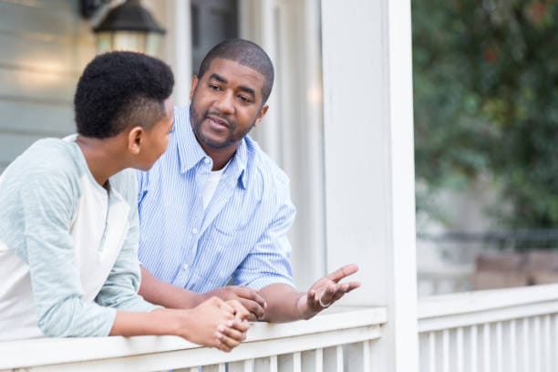African American father and son talking outside of the house