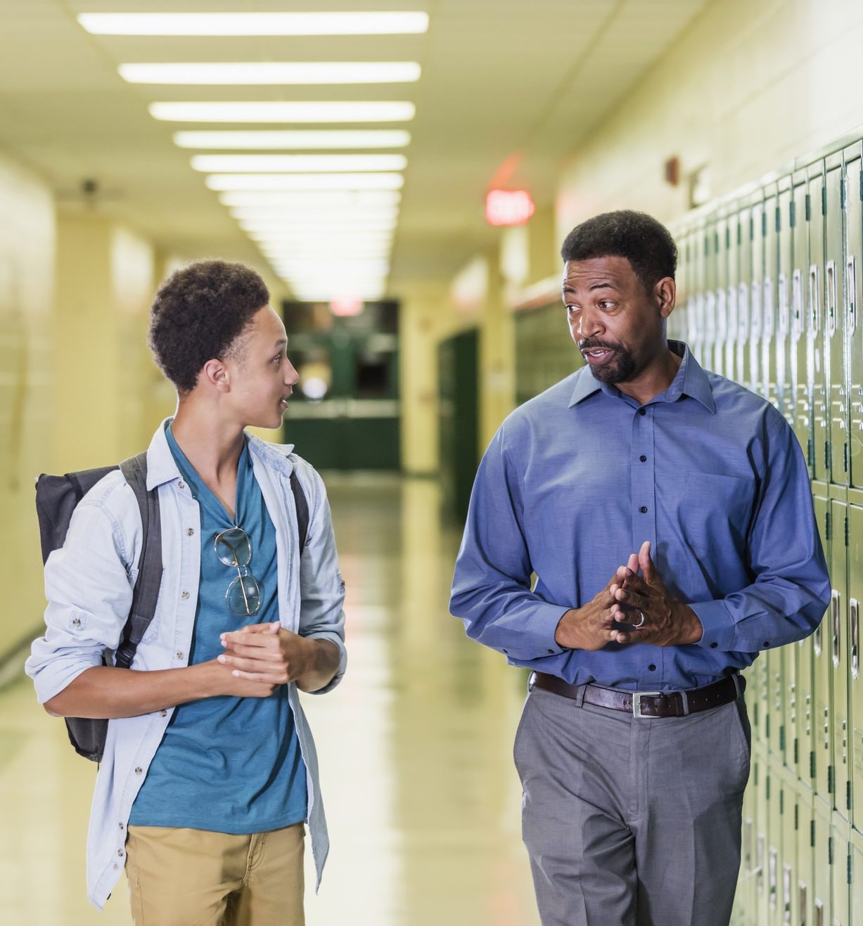 Teacher and teenage student walking in school hallway