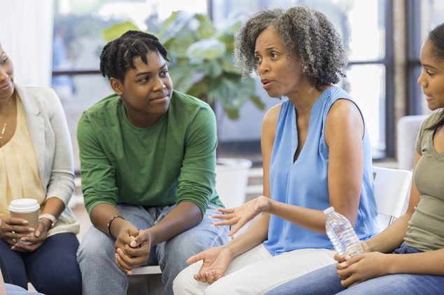 Female counselor advises people during support group meeting