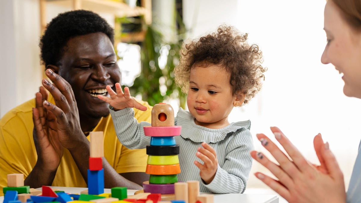 A child playing with blocks with parents