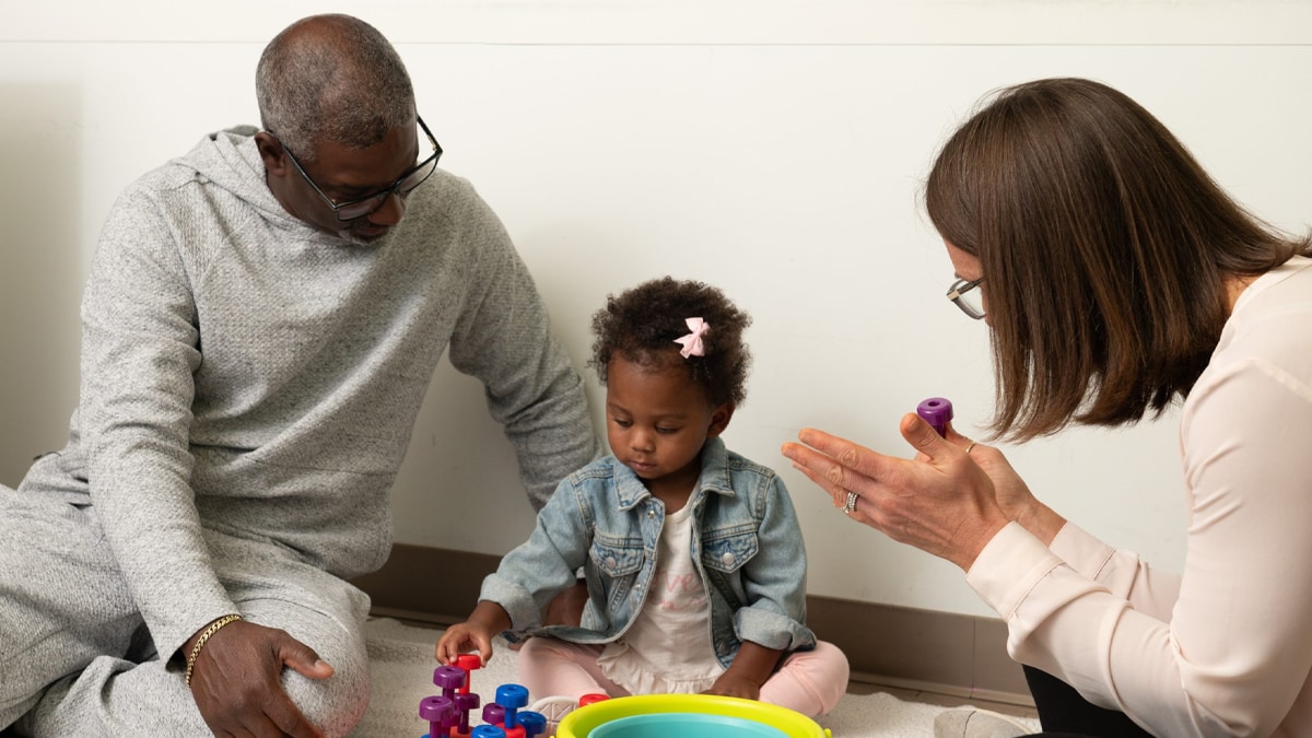 An infant and her father participate in early intervention services