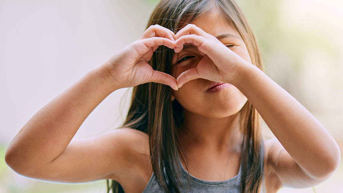 A little girl making a heart sign with her hands