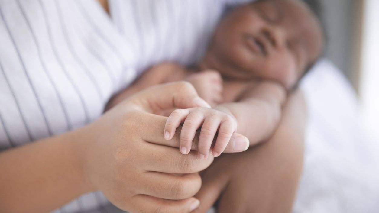 A caregiver holding a baby's hand